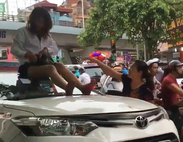 Nữ tài xế taxi mặc váy ngồi nóc ô tô chống đối CSGT