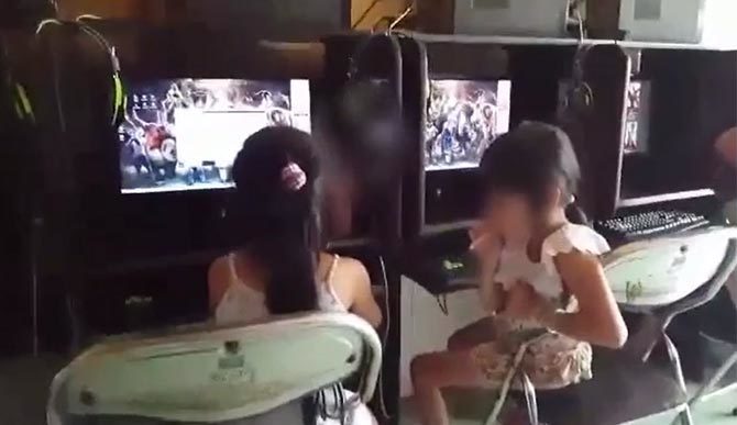 Hai bé gái 6 - 7 tuổi vừa hút thuốc vừa chơi game
