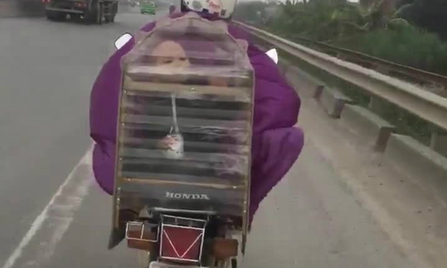 Mẹ đi xe máy chở con trong lồng chim để tránh rét?