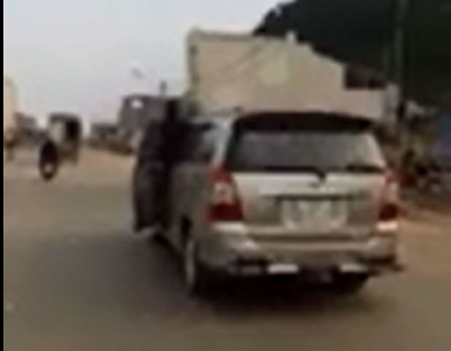 Người phụ nữ vừa lái xe, vừa mở cửa nhoài người ra nói chuyện điện thoại